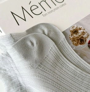 Close-up of light gray knitted sock showing breathable hollow texture and reinforced heel