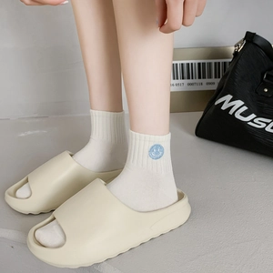 Chic beige EVA platform slides worn with white cotton socks featuring a blue smiley face