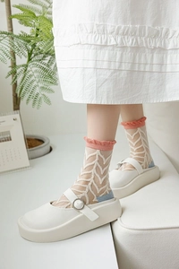 Gros plan de chaussettes en tulle à motifs de feuilles et volants roses avec Mary Janes