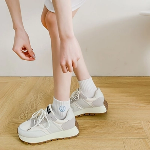 Close-up of beige thick-soled sneakers with non-slip rubber outsole and smiley face socks