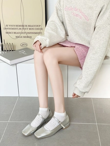 Détail de socquettes blanches ajourées avec des chaussures Mary Jane argentées à bout carré