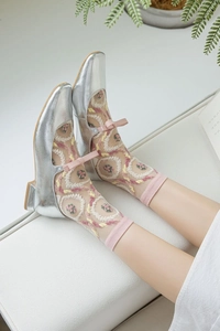 Détail de chaussures Mary Jane argentées avec chaussettes en résille à broderie rose