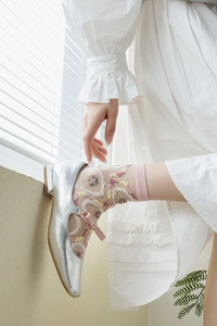 Détail de chaussettes en tulle brodé de fleurs avec des chaussures Mary Jane argentées