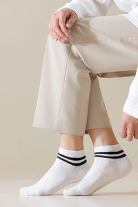Detailed view of white cotton low cut socks with black stripes on a male model