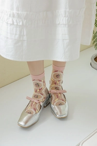 Détail de chaussettes en tulle rose brodé avec chaussures Mary Jane argentées