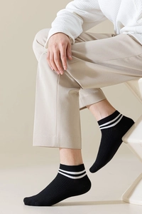 Detail of black knit low cut socks with white stripes on a foot showing soft texture