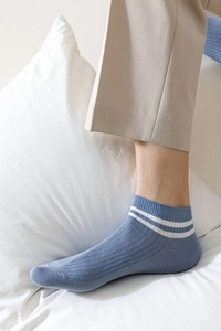 Detail of blue cotton blend low-cut socks with white stripes on ribbed cuff worn by model