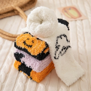 Détail de chaussettes d'Halloween en polaire corail orange et violette sur un plaid