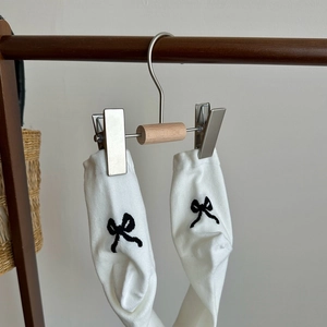 Detail of white cotton ankle socks with black bow embroidery on a wooden hanger