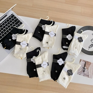 White and black sheer crew socks with ruffle edges and cute charms on a desk