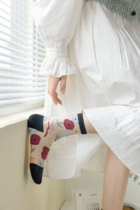 Détail de chaussettes en soie transparente avec broderie florale et bords noirs
