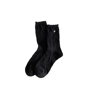 White background photo of black ruffle trim crew socks with silver flower charm