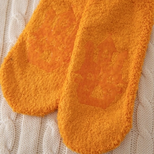Gros plan de chaussettes en polaire corail orange avec picots antidérapants en château