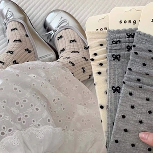 Détail de chaussettes en maille avec motifs nœuds noirs et bords côtes festonnés