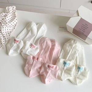 Three pairs of mesh knit socks with bow accents in white, pink and beige tones