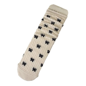 Chaussettes mi-mollet beiges en coton avec motifs nœuds noirs et texture côtelée sur fond blanc