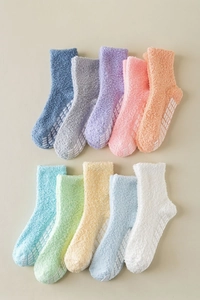 Detail of colorful fuzzy socks showing thick coral fleece texture and non-slip grippy dots