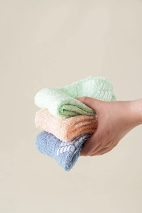 Close-up of thick fuzzy socks with non-slip grippers in green, pink and blue colors