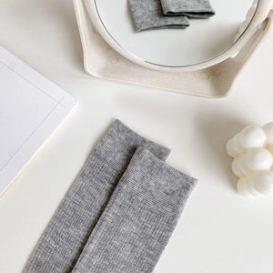 Detail of grey mesh knit socks with bow and ribbed texture on a white surface
