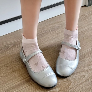 Close-up of silver Mary Jane shoes with mesh bow socks on light wooden floor