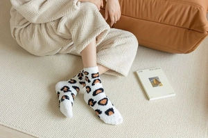 Close-up of leopard print coral fleece socks in a cozy home setting with warm lighting