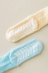Close-up of fluffy coral fleece socks with white anti-slip silicone grippers on the sole