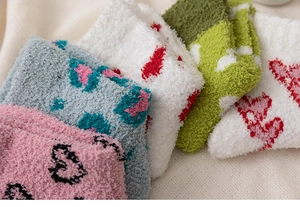 Gros plan de chaussettes d'hiver en polaire corail avec motifs de cœurs et léopard colorés