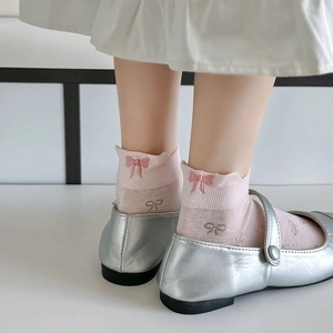 Close-up of pink cotton ankle socks with bow embroidery and silver Mary Jane shoes