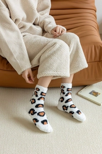 Close-up of leopard pattern coral fleece socks worn by a person in a cozy home setting