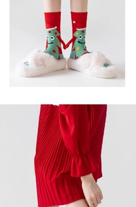 Detail of red Christmas magnetic hand-holding socks with tree patterns and plush slippers