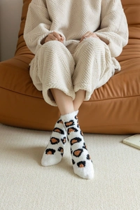 Close-up of leopard print coral fleece socks worn in a cozy indoor home setting
