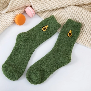 Detail of green coral fleece socks with avocado embroidery on soft knit blanket