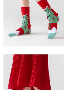 Detailed close-up of knitted Christmas tree socks paired with a red pleated skirt