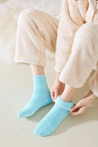 Detail of light blue fuzzy coral fleece socks with anti-slip silicone dots for winter warmth