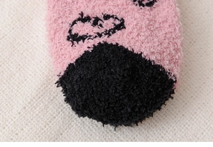 Gros plan détaillé des chaussettes d'hiver en polaire corail avec motif de cœur noir