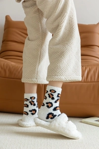 Detailed view of leopard print coral fleece socks paired with plush home slippers