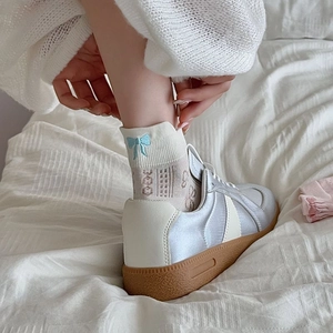 Detail of silver metallic trainer with white ankle sock featuring blue bow embroidery