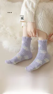 Detail of thick purple coral fleece socks with floral patterns on a white carpet