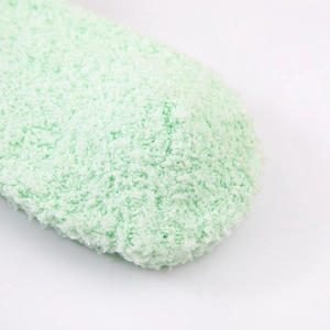 Close-up of soft light green coral fleece fabric texture on a warm winter sock