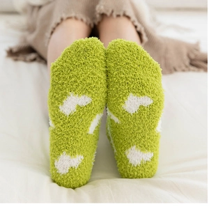 Gros plan de chaussettes d'hiver en polaire corail avec motifs de nuages blancs en vert