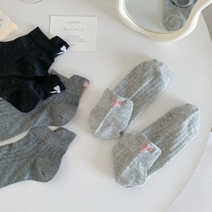 Close-up of knit ankle socks with ribbed texture and delicate bow embroidery details