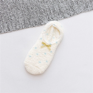Detailed view of plush coral fleece floor socks with blue polka dots and a yellow bow
