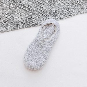 Close-up of plush light gray floor socks featuring lace edges and non-slip silicone dots