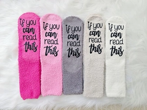 Close-up of five colorful fuzzy coral fleece socks with 'If you can read this' text