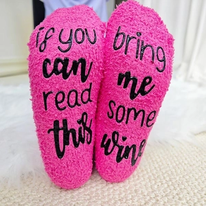 Detailed texture of thick hot pink fuzzy socks with funny wine quote on soles