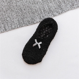 Close-up of black fuzzy floor socks with silver bow and anti-slip silicone dots