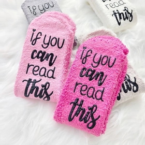 Thick fuzzy coral fleece warm socks with anti-slip text on plush white carpet