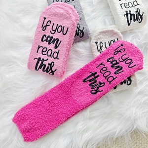 Close-up of thick coral fleece socks featuring if you can read this text on the sole