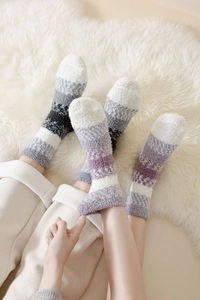 Gros plan de chaussettes thermiques rayées en polaire sur un tapis moelleux