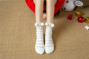 Detail of coral fleece socks with bear embroidery and plush balls in Christmas setting